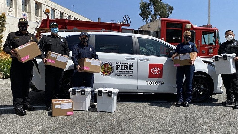 Toyota Sienna with community members holding donation boxes